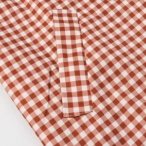 Vue macro d'une poche à double surpiqûre sur tissu vichy rouge et blanc de manteau