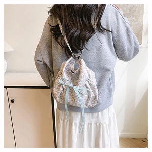 Detail of floral nylon backpack featuring blue ribbon bow and drawstring closure