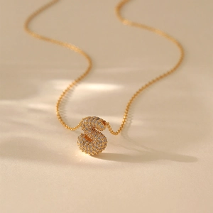 Macro detail of gold S-letter pendant necklace with sparkling pavé zircon setting