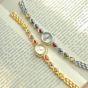 Luxury oval jewelry watch with colorful rainbow gemstones and a stylish chain strap