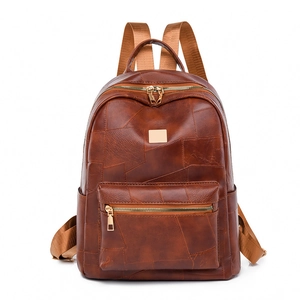 Detailed view of dark brown leather backpack with gold zippers and fabric straps