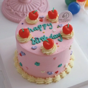 Gros plan d'un gâteau d'anniversaire rose de style coréen avec de jolies bougies cerises.