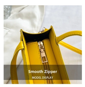 Détail de la fermeture éclair en métal doré sur le sac à main jaune en similicuir