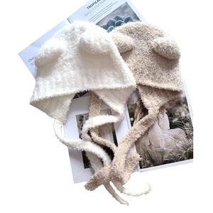 Detail of white and beige knit hats with animal ears and long straps on a magazine