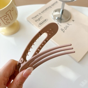 Close-up of matte brown plastic duckbill hair clip with sleek three-line curved design