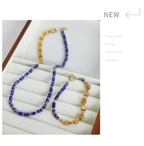 Detail of luxury necklace and bracelet set with blue marble beads and gold braided metal