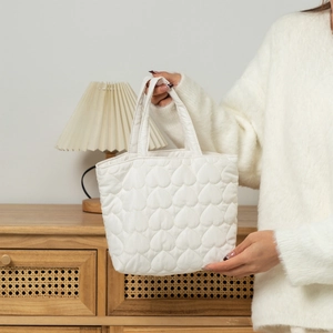 Close-up of white quilted tote bag featuring padded heart patterns and soft texture