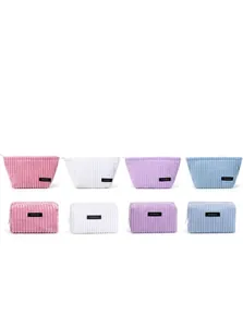 Detail view of plush textured cosmetic bags in pink, white, purple, and blue colors