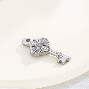 Polished stainless steel clover key pendant for DIY jewelry on white circular base