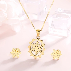Detailed view of golden snowflake necklace and earrings set on a soft pink background