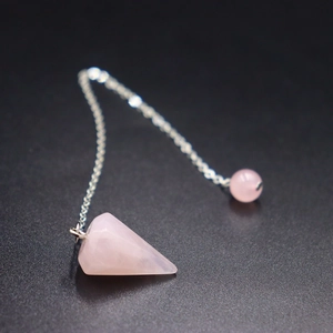 Detail eines Rosenquarz-Pendels mit sechseckiger Form und feiner silberner Metallkette