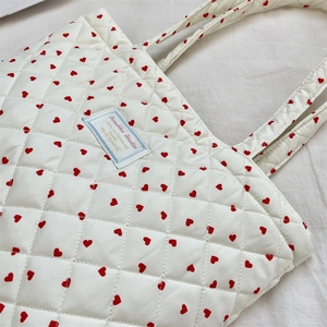 Détail du sac cabas matelassé avec cœurs rouges et étiquette de marque Somkka Studio