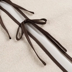 Vue macro du ruban en satin marron sur le tissu en polaire sherpa beige