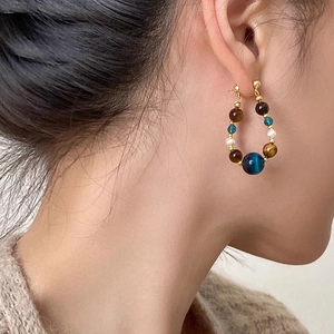 Boucles d'oreilles créoles perlées avec œil de tigre et perles portées par un mannequin