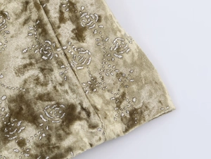 Detailed macro view of olive velvet fabric with shimmering silver rose floral patterns