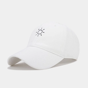 Detail of white cotton baseball cap showing sun embroidery and twill fabric texture
