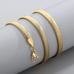 Macro shot of a polished golden snake bone chain necklace with a lobster clasp