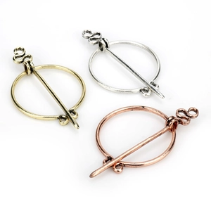Three-color metal Viking cloak pins in gold, silver and rose gold finishes on white background
