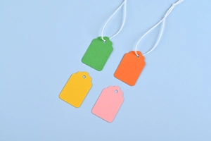 Detail of green, orange, yellow, and pink blank paper price tags with white strings