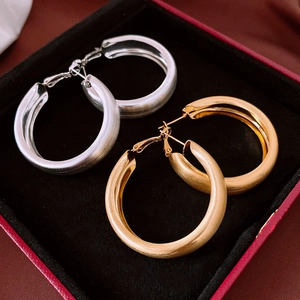 Detail view of gold and silver plated thick hoop earrings with a brushed matte finish texture