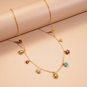 Macro view of gold chain necklace featuring colorful ladybug and flower charms with cubic zirconia