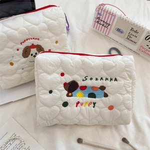 Close-up of white heart-quilted cosmetic bag with cute puppy embroidery and red zipper