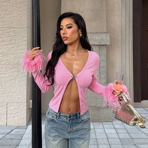 Détail du cardigan en maille rose avec poignets en plumes d'autruche et décolleté en V