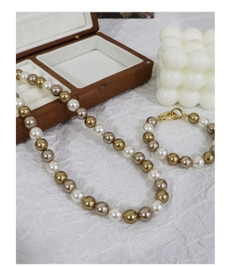 Detail view of a multi-color pearl necklace and bracelet set with golden ring clasps