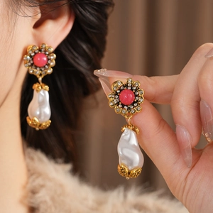 Detail of vintage flower earrings with pink crystal and baroque pearl on model