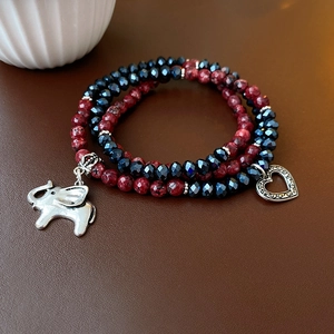 Macro shot of multi-layer beaded bracelet with elephant charm and heart pendant on leather