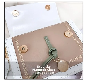 Detail view of khaki and white crossbody bag with gold magnetic snaps and charm