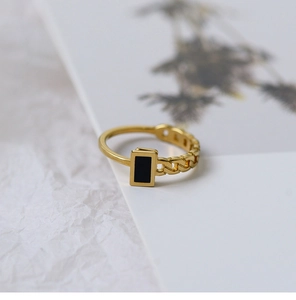Detail of 18K gold-plated chain ring with a black rectangular insert on textured white paper