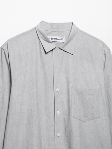 Close-up of light gray long sleeve shirt with classic collar, button-up and front pocket