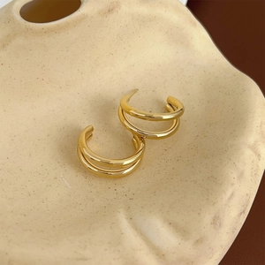 Close-up of polished golden double hoop earrings on minimalist ceramic texture
