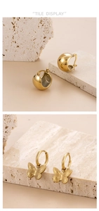 Detailed view of polished gold butterfly earrings displayed on a minimalist stone