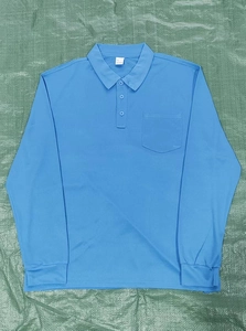 Detail of light blue long sleeve polo shirt with chest pocket and three buttons