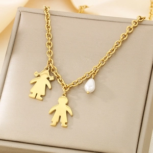 Close-up of gold chain with girl and boy silhouette pendants and a white pearl drop