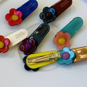 Detailed close-up of colorful resin flower hair clips with golden metal duckbill clips