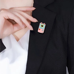 Pink retro game console enamel pin styled as a cute brooch on a black suit lapel