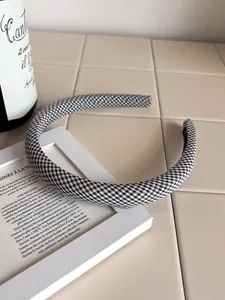 Detail of black and white gingham checkered wide sponge headband on a beige counter
