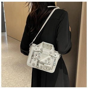 Close-up of a white motorcycle jacket style crossbody bag with silver floral studs