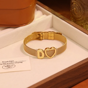Détail du bracelet en maille dorée avec pendentifs cœur et lettre D en gros plan