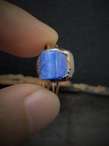 Detail of a vintage adjustable ring with a blue rectangle gemstone in a bronze wire wrap
