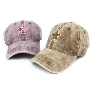 Detailed view of washed denim baseball caps featuring sequined star patches in purple and khaki