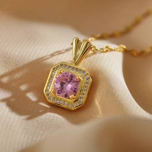 Detailed macro view of a gold-plated square pendant with pink and clear zircon crystals