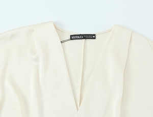 Detailed view of cream silk satin V-neck blouse featuring refined collar and brand tag