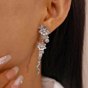Détail des boucles d'oreilles fleurs argentées avec pompon et feuilles sur modèle