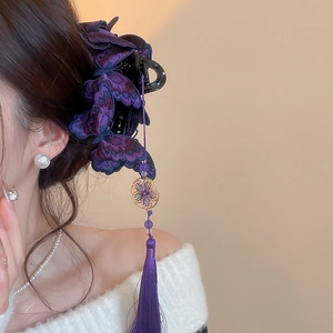 Dettaglio del fermaglio per capelli a farfalla ricamata viola con frange lunghe e fiore oro