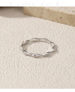 Macro shot of polished silver bamboo joint ring on minimalist beige textured background