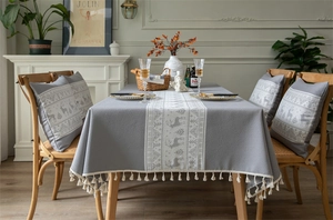 Detailed view of grey Christmas tablecloth featuring white reindeer patterns and fringe edges